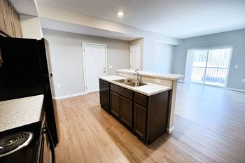 An empty kitchen and living room with wood flooring and